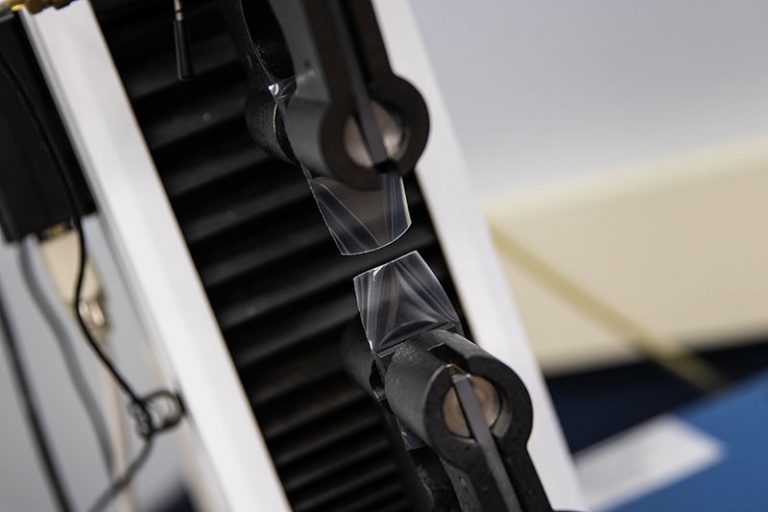 Strain gauge and tensile testing equipment used for measuring material strength and elasticity in packaging and manufacturing.